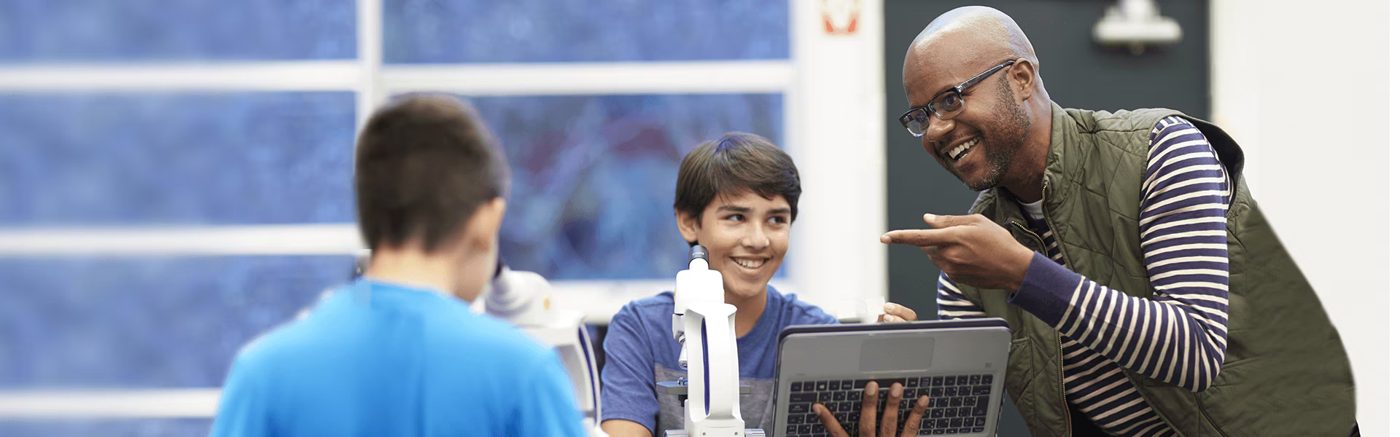 An educator mentoring a student working on a laptop
